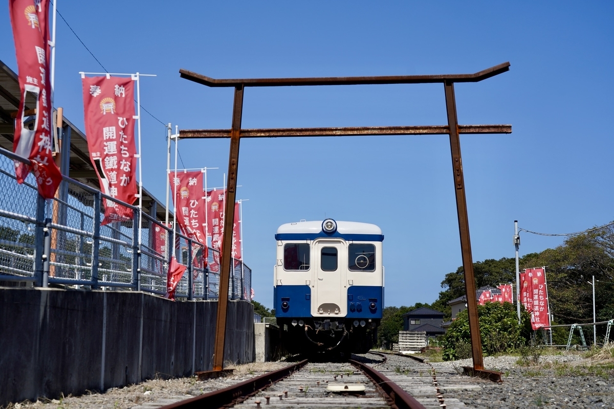 Recinto del Santuario Ferroviario Kaiun de Hitachinaka con un coche diesel KiHa azul y blanco estacionado detras de un torii hecho de rieles oxidados