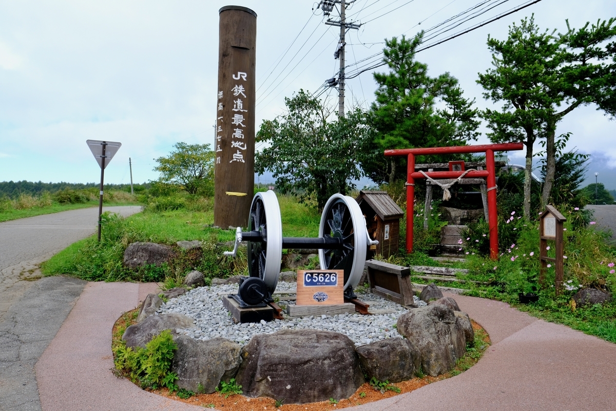 Santuario del Punto Mas Alto Ferroviario con un marcador de madera del punto mas alto ferroviario de JR, ruedas de locomotora de vapor veneradas sobre bases de piedra y un torii rojo