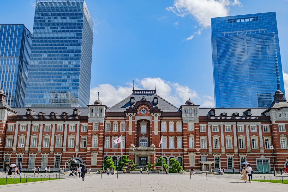 Fachada de ladrillo rojo del edificio de la Estacion de Tokio Marunouchi bajo cielos azules con edificios de gran altura a ambos lados
