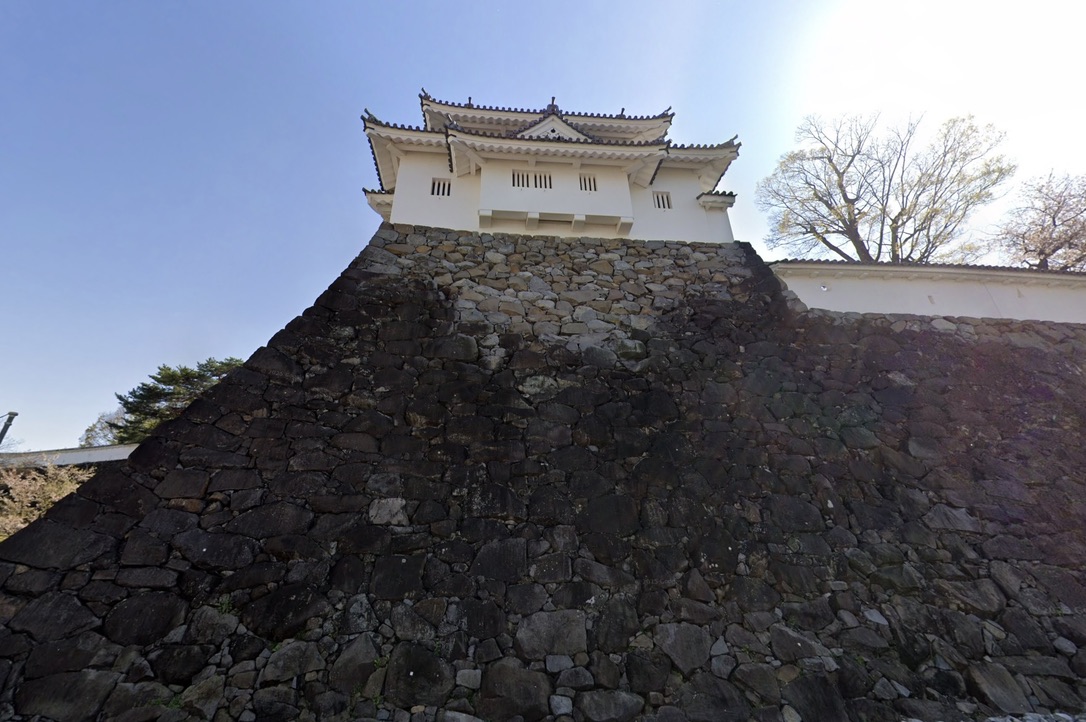 천수대의 석벽을 아래에서 올려다본 흰 벽의 망루와 기와지붕