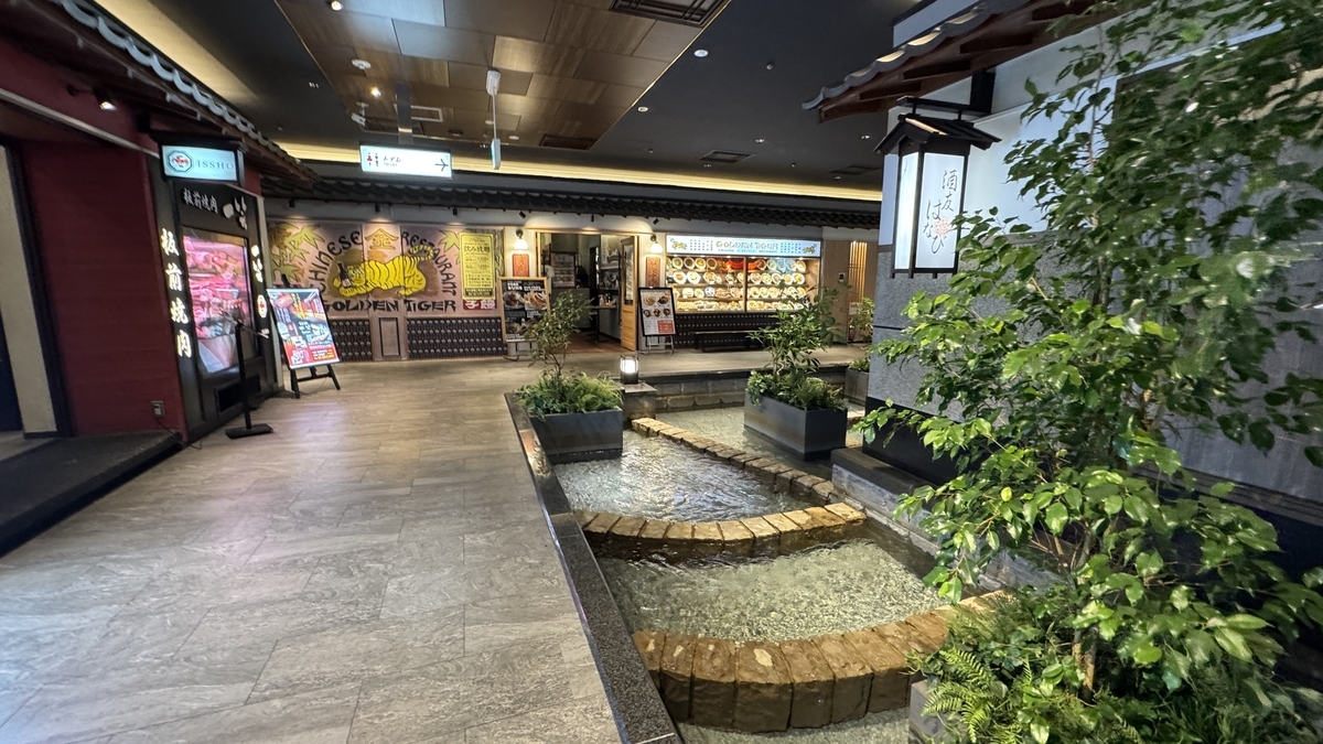 돌 바닥의 작은 개울과 식물이 배치된 우메다 시바치카 통로와 매장 간판