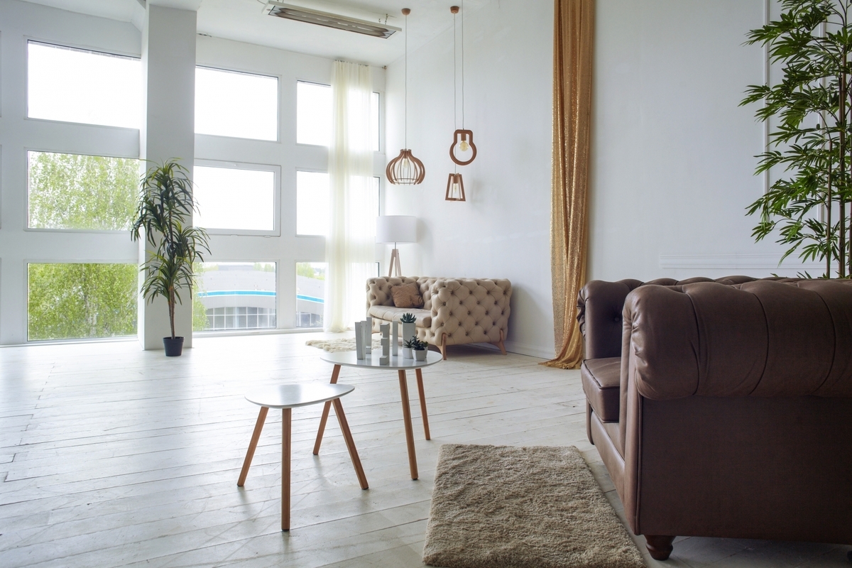 大きな窓から柔らかな光が差し込む白い床のリビングとソファと丸テーブル