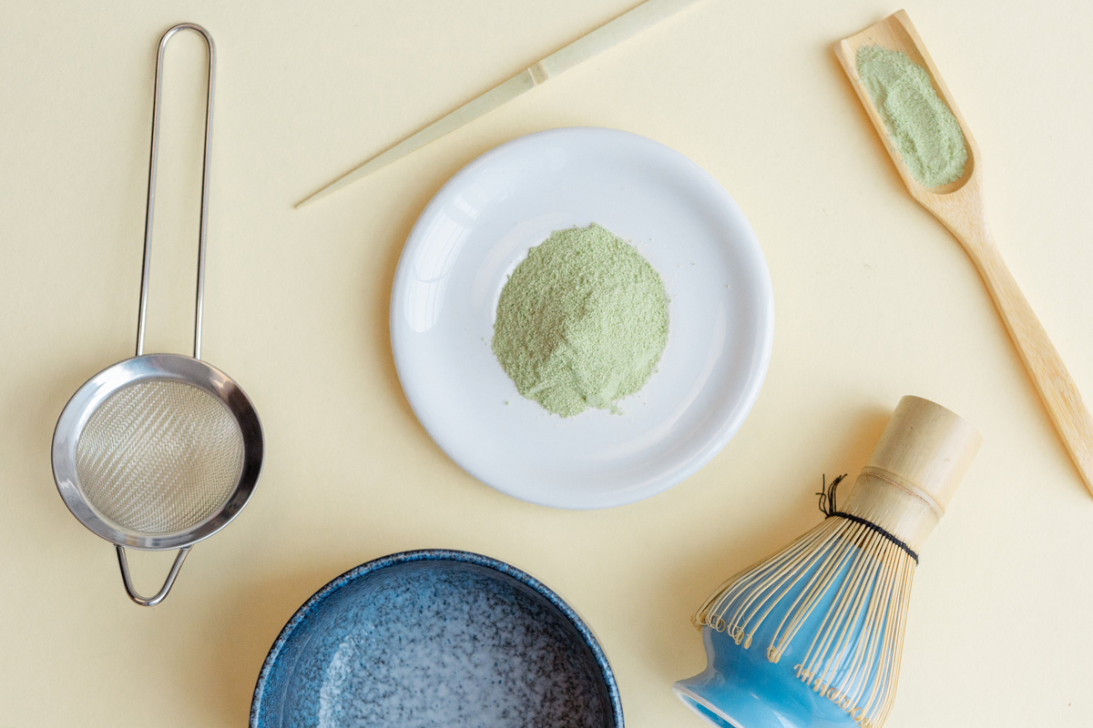 抹茶の道具一式の俯瞰で茶漉しと茶杓と抹茶粉末の皿と茶碗と茶筅