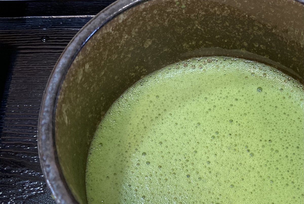 黒い盆の上に置かれた茶碗の中で泡が立った薄茶