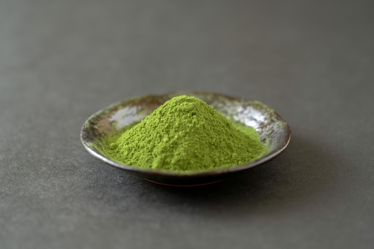 黒い小皿に山のように盛られた鮮やかな抹茶粉末