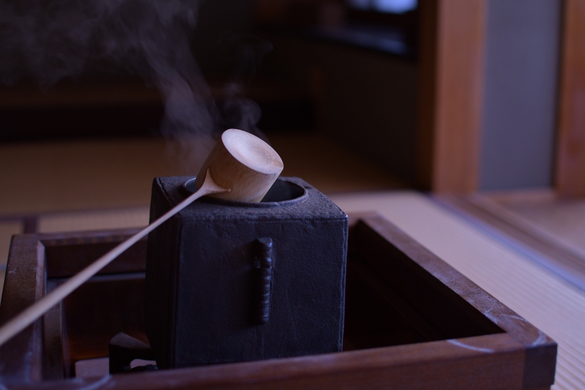湯気が立つ炉に木製の柄杓を置いた茶道の湯沸かし道具