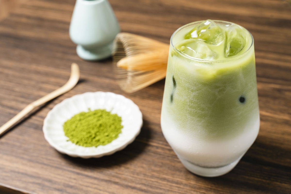 氷入りグラスのアイス抹茶ラテと抹茶粉末の小皿と茶筅