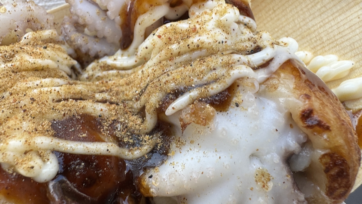 Close-up of takoyaki generously topped with sauce, mayonnaise, and aonori