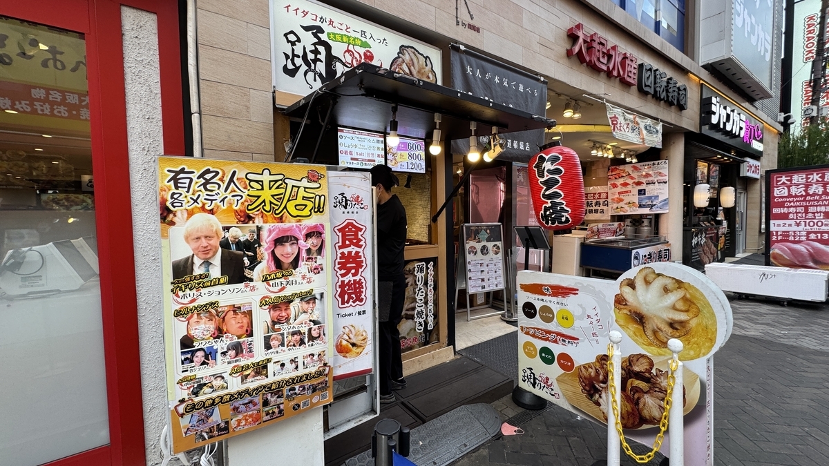 Full exterior view of Odoridako storefront with red lanterns and menu signs in Dotonbori