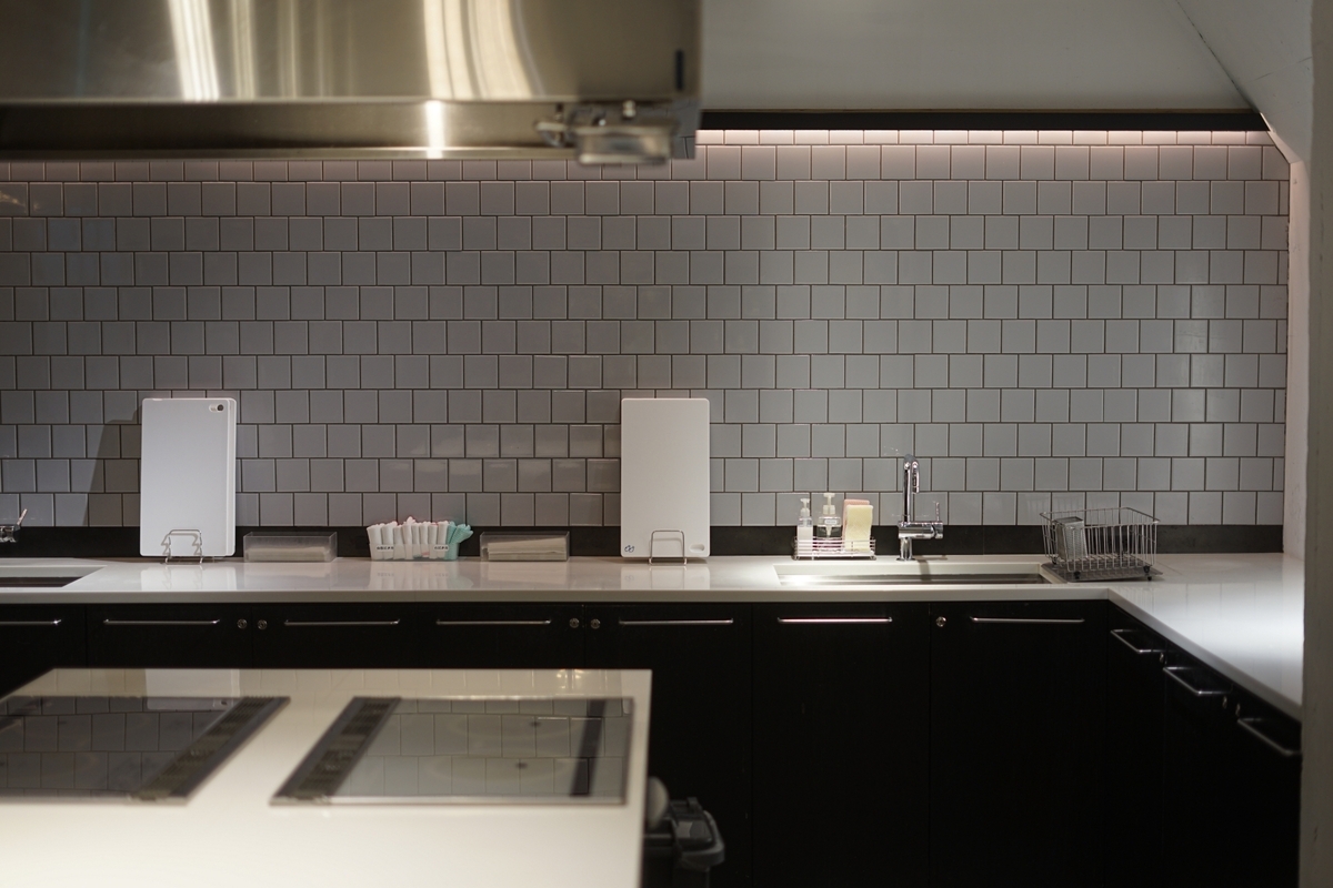 A clean kitchen counter with white tiled walls and a sink