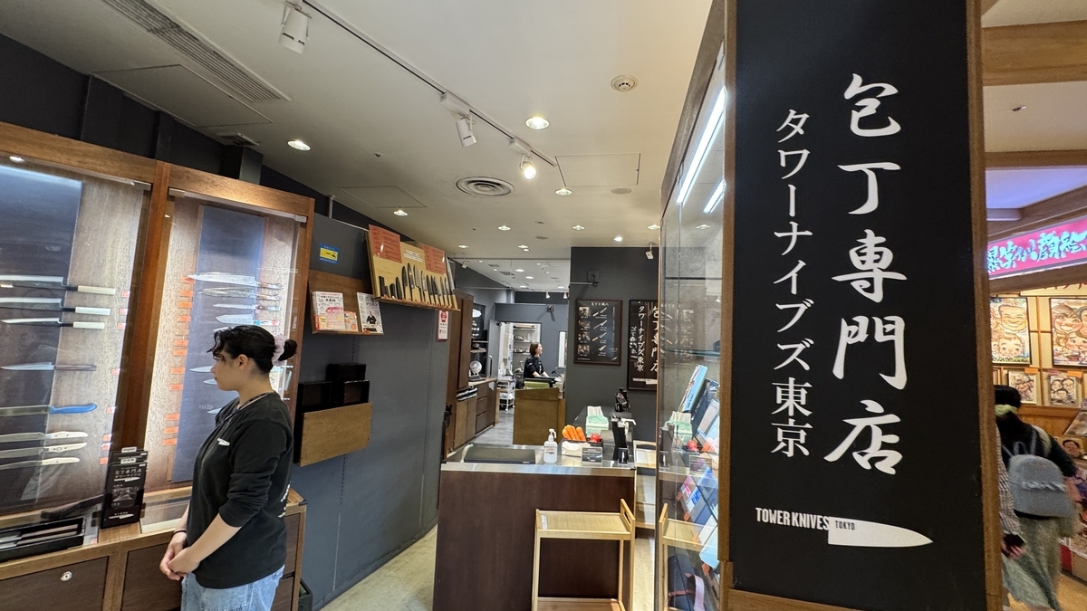 Staff guiding visitors at the entrance of Tower Knives Tokyo with display shelves of knives
