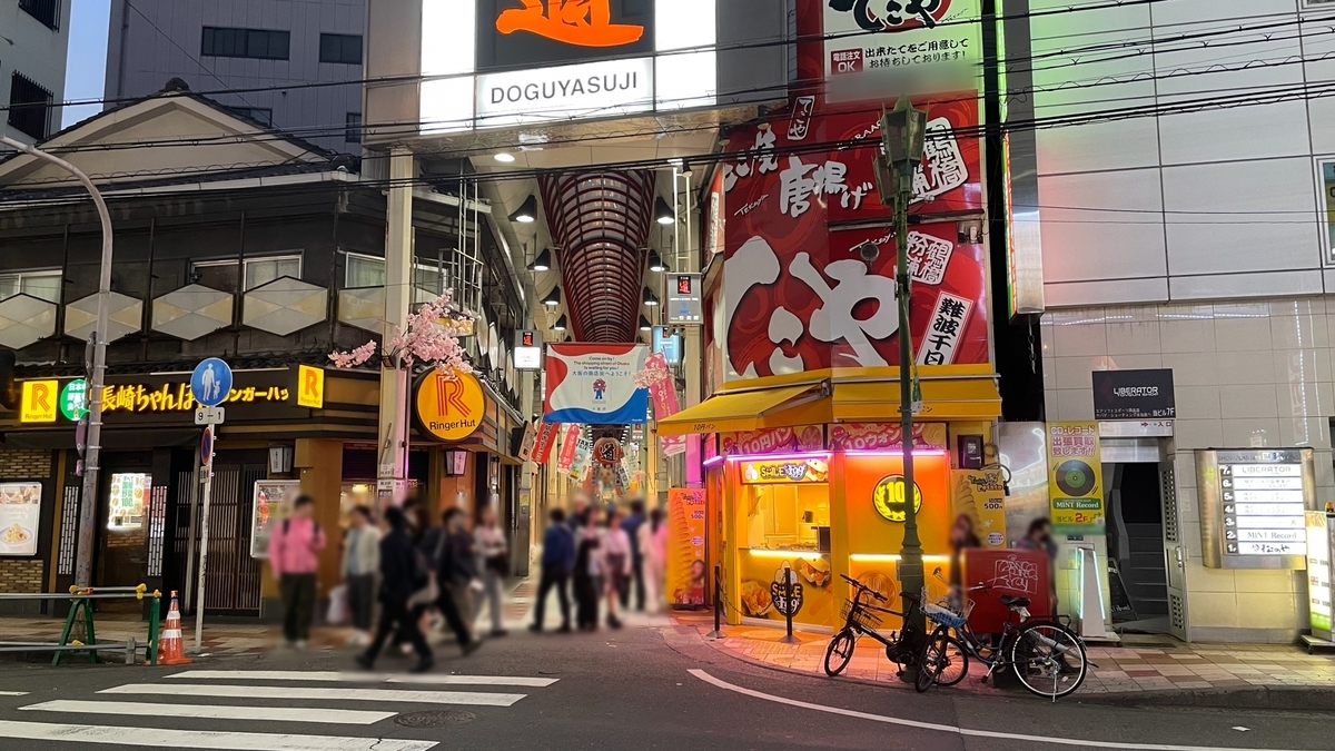 Entrance sign and red archway of Sennichimae Doguyasuji Shopping Street with evening foot traffic