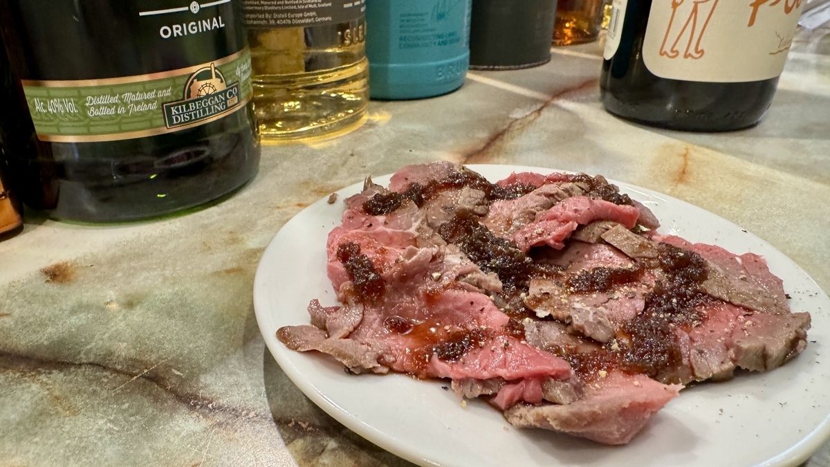 薄切烤牛肉擺盤，撒上粗粒黑胡椒和醬汁