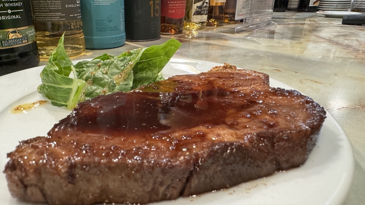 厚實的豬排淋上光澤醬汁，搭配白盤上的綠葉蔬菜