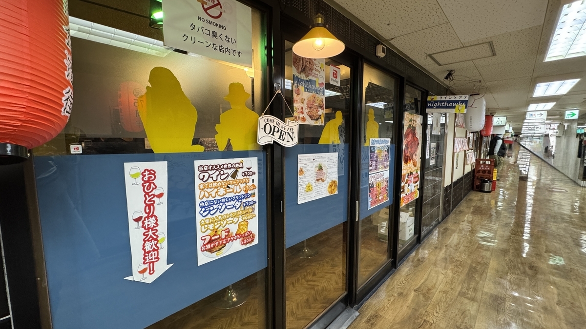 nighthawks外觀展示藍色下牆和黃色剪影，入口處有歡迎一個人來的招牌