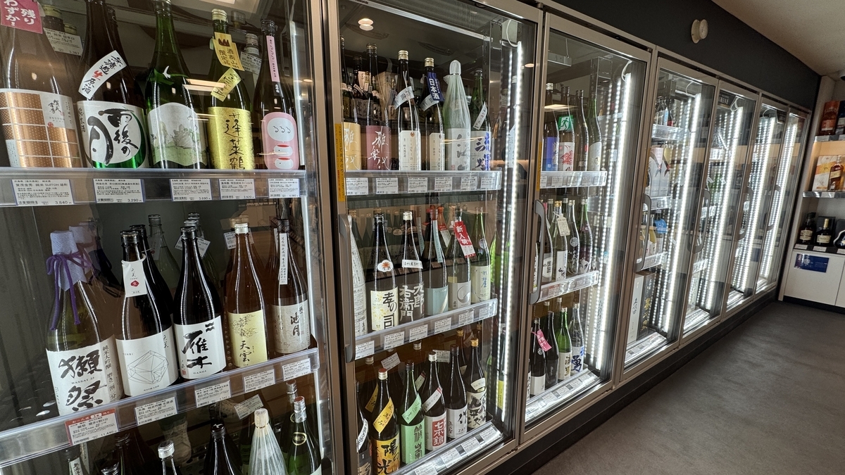 ขวดสาเกมากมายเรียงรายในตู้แช่เย็นของร้านขายเหล้า