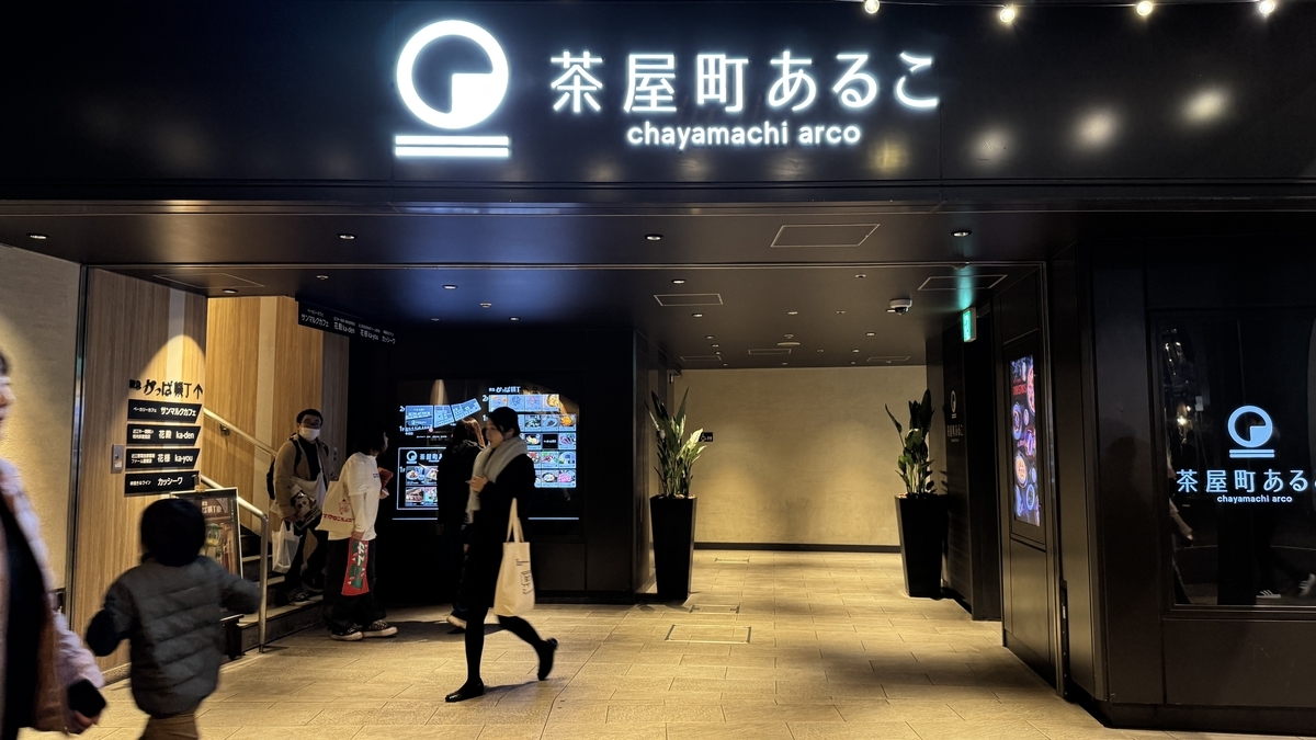 차야마치 아루코의 검은 외관 간판과 안내 모니터 앞을 지나가는 방문객들