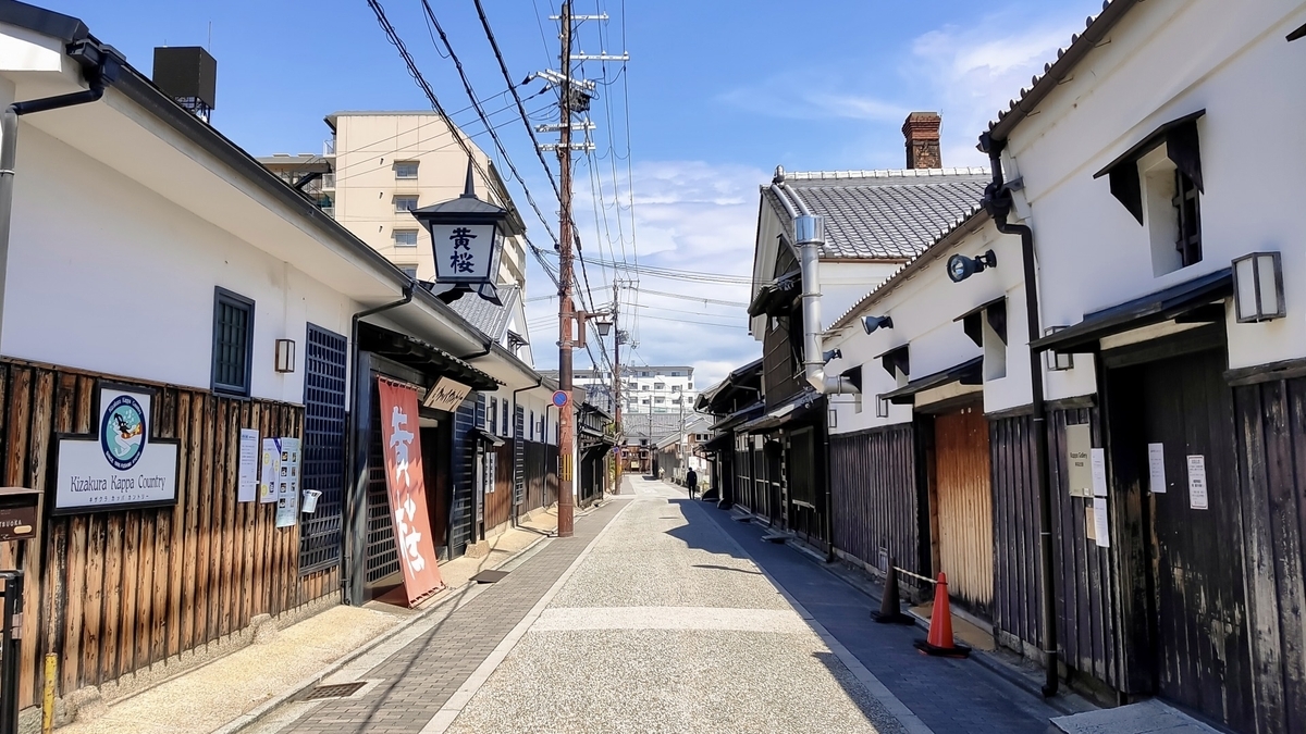 흰 벽과 나무 격자가 이어지는 후시미 양조장 거리의 풍경