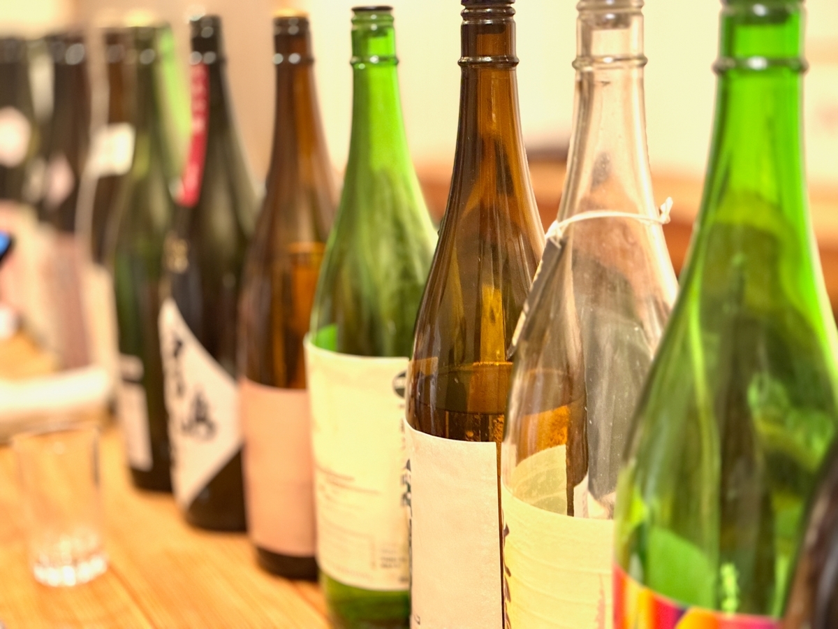 가쿠우치 카운터에 일렬로 나란히 놓인 사케 병과 빈 잔