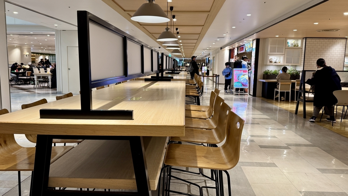 모자이크 패턴 긴 테이블과 장식 조명이 보이는 미아 키친 앞 공용 다이닝 공간