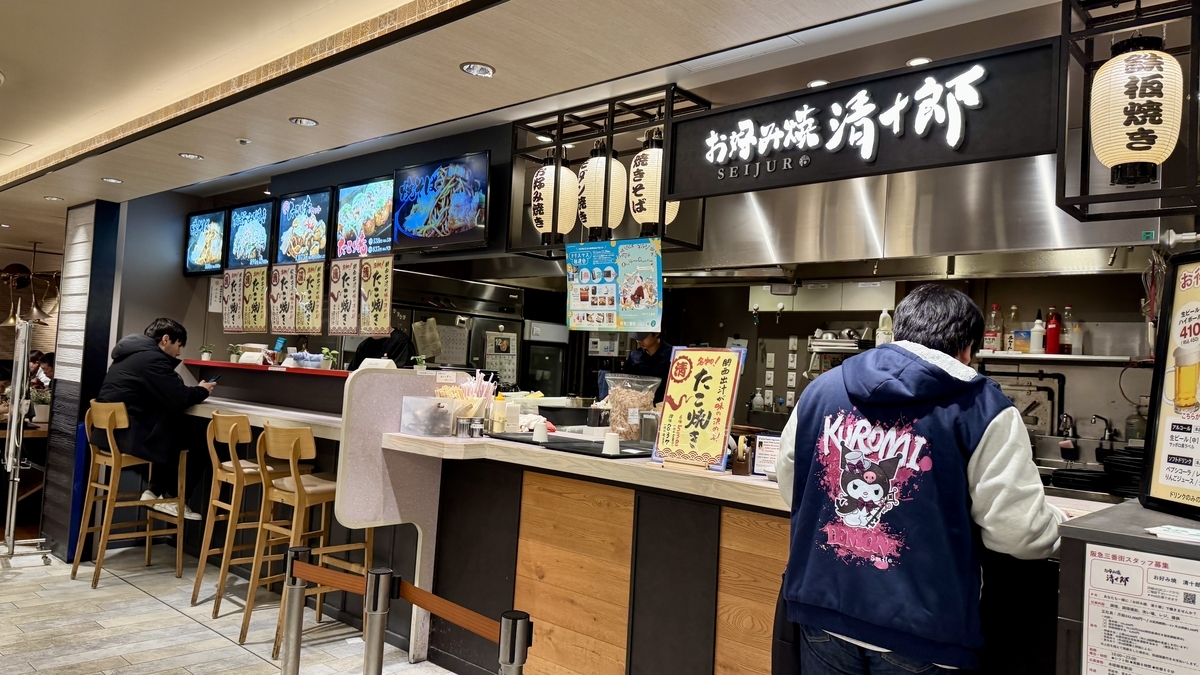 등불과 큰 메뉴 간판이 늘어선 오코노미야끼 세이주로의 카운터 매장 외관