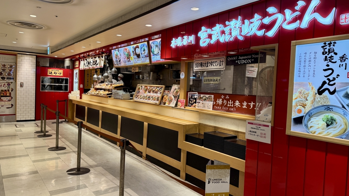 빨간 외벽에 큰 상호명이 돋보이는 미야타케 사누키 우동의 긴 주문 카운터