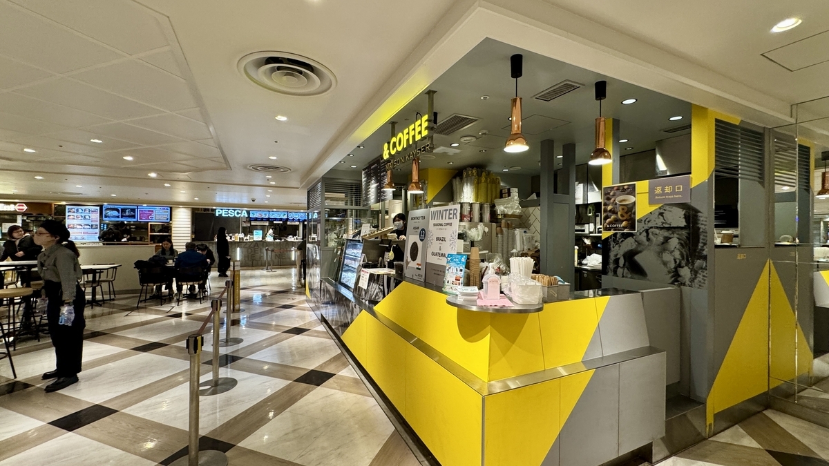 노란 카운터가 돋보이는 &COFFEE 메종 카이저와 뒤편에 보이는 푸드홀 공용석