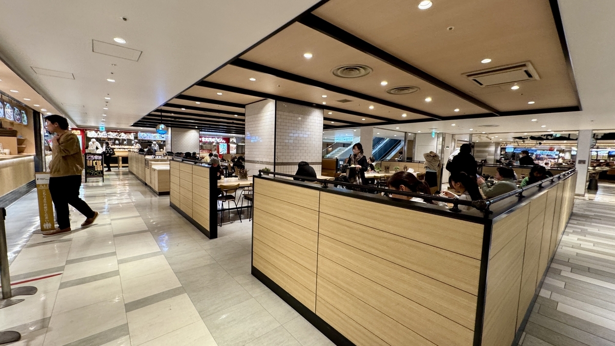 나무 칸막이 좌석이 줄지어 있는 UMEDA FOOD HALL의 넓은 다이닝 에어리어