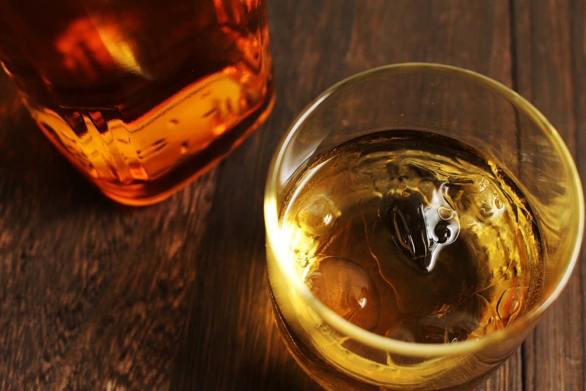 木のテーブルに置かれた氷入りウイスキーのグラスとボトル