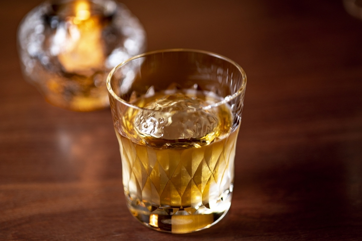 上から見た氷入りウイスキーグラスと左上に写るボトル