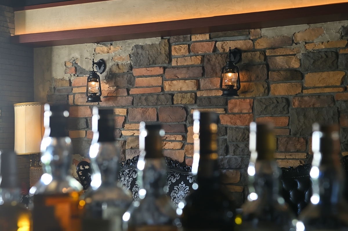石壁とランタン照明の前で手前のボトル群がぼけて写るバー空間