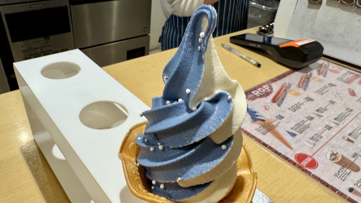 吧台上一支蓝白双色的鲸鲨冰淇淋,背景是菜单展示板