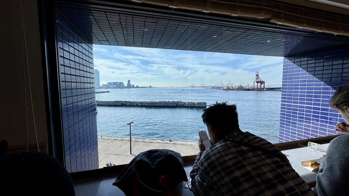 游客在临窗吧台座位上休息,眺望大阪湾