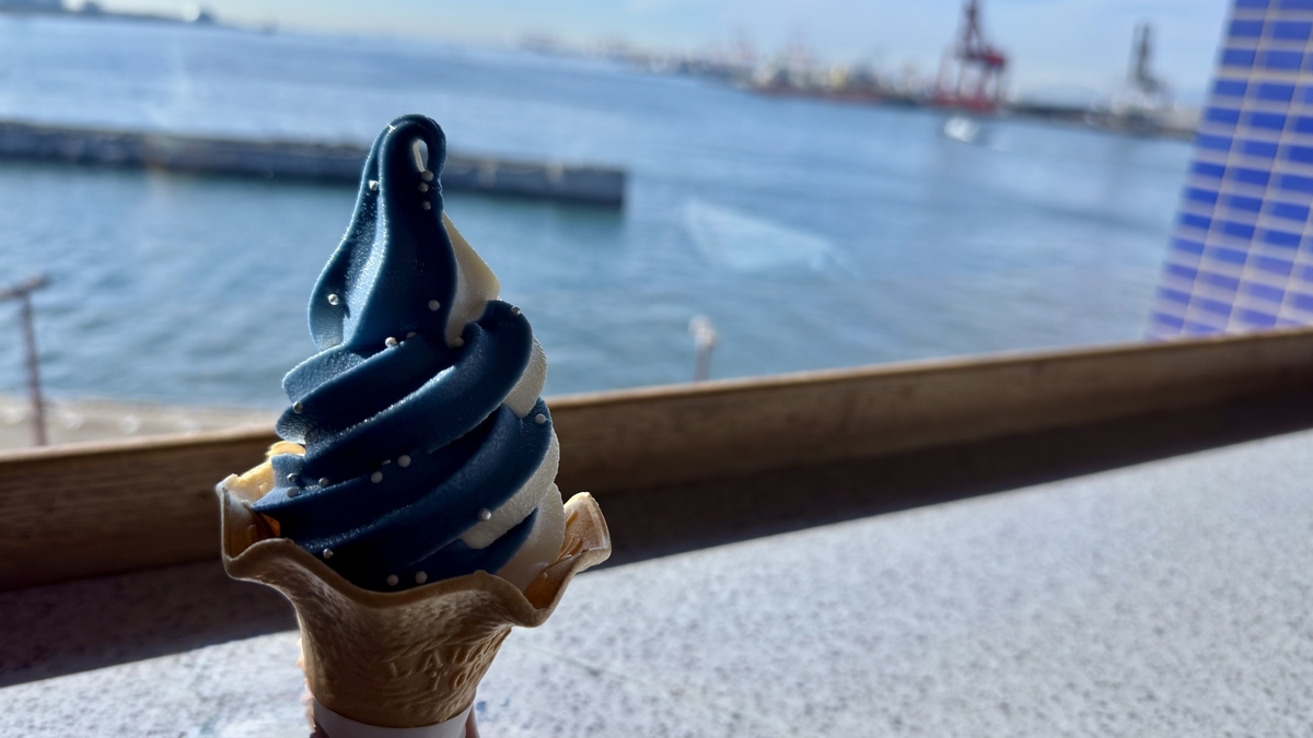 一支鲸鲨冰淇淋放在临窗吧台上,背景是大阪湾