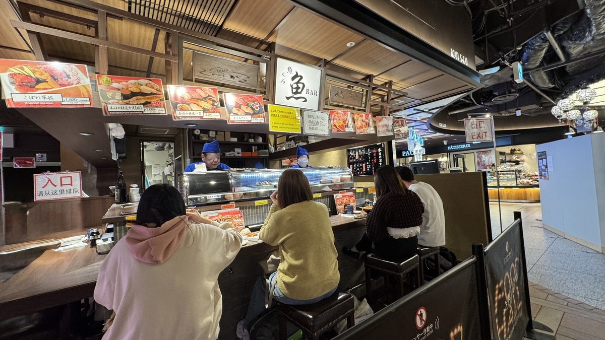 魚BARのカウンター席で寿司を味わう来店客