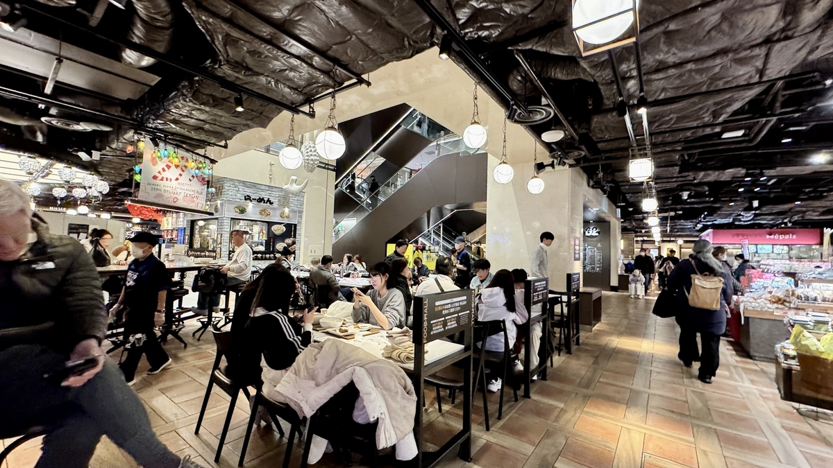 エスカレーター前の共有席と行き交う来店客で賑わう店内