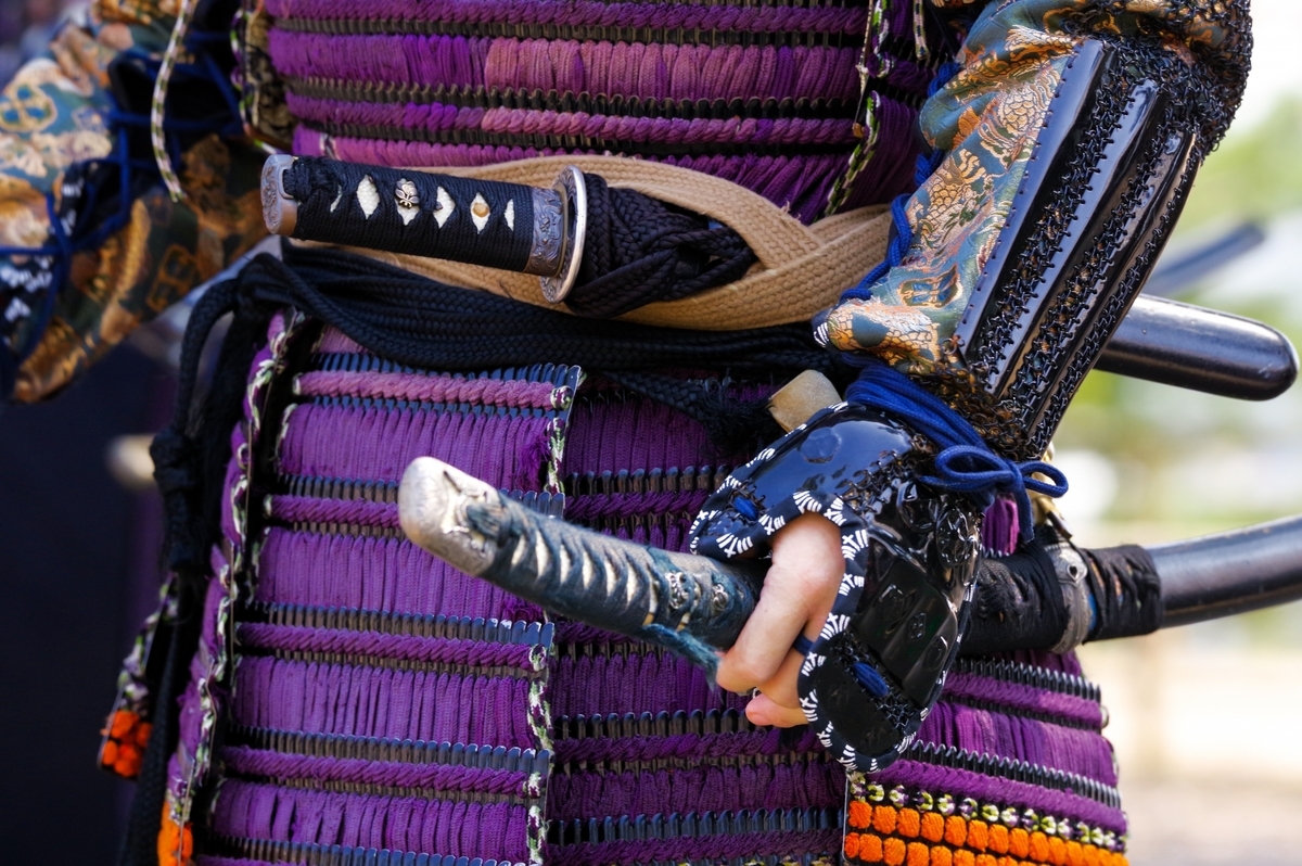 보라색 끈으로 엮은 갑옷을 입고 칼을 쥔 사무라이의 손