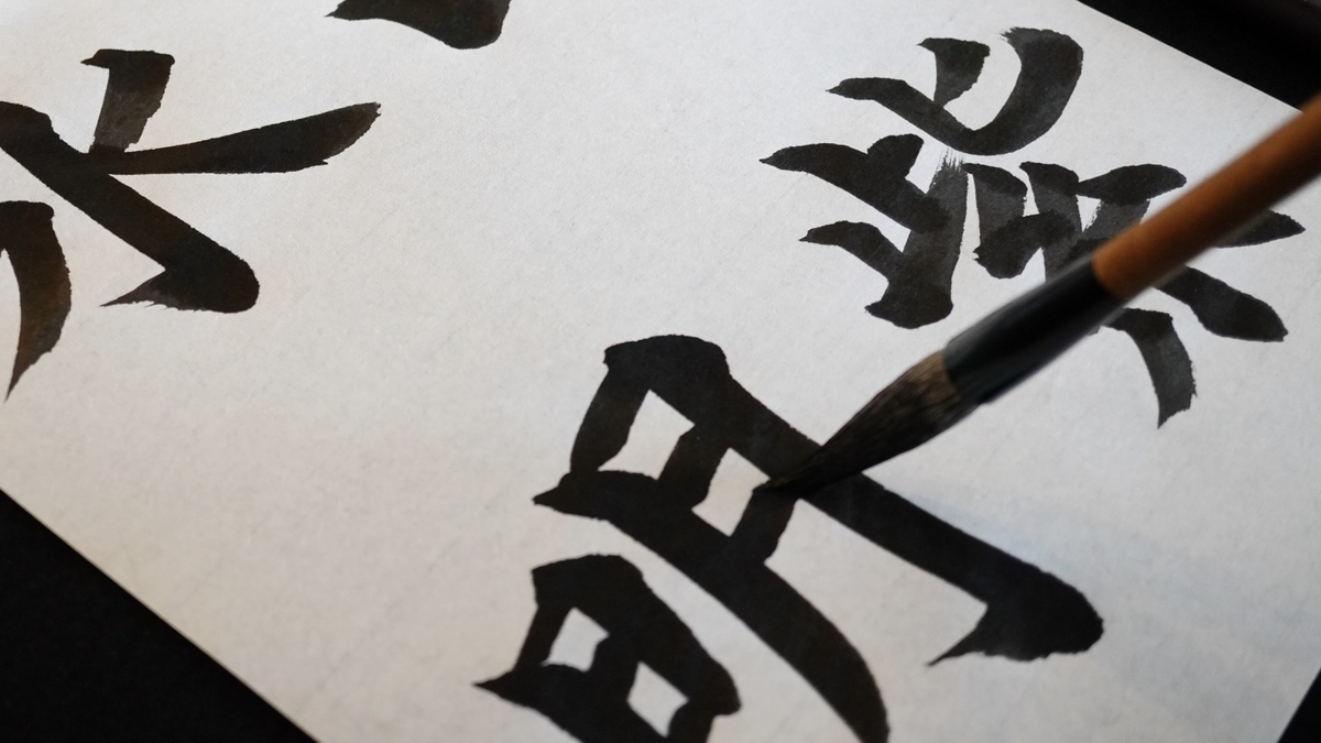 붓으로 큰 한자를 쓰고 있는 서예 장면