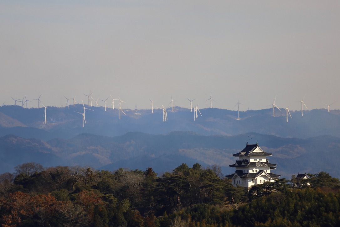 산등성이와 풍차를 배경으로 서 있는 하얀 성