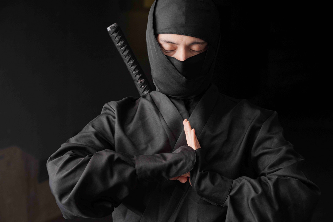 검은 닌자 복장으로 인(印)을 맺는 인물