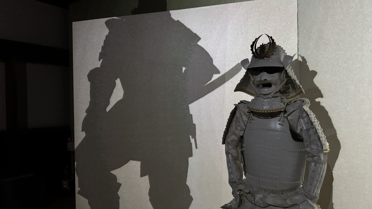 大きな影が映る花伐つ鎧の白い甲冑
