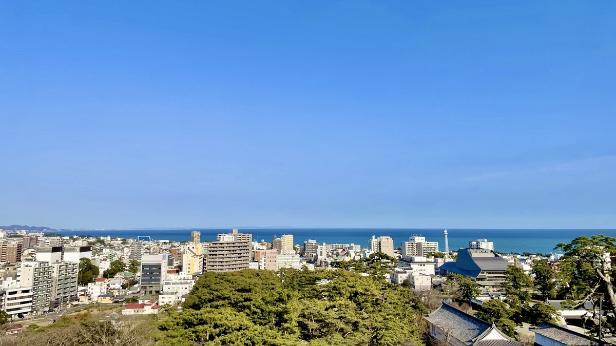 青空の下に広がる小田原市街地と相模湾の眺め