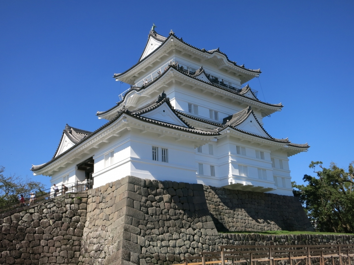 青空の下で石垣の上にそびえる小田原城天守閣