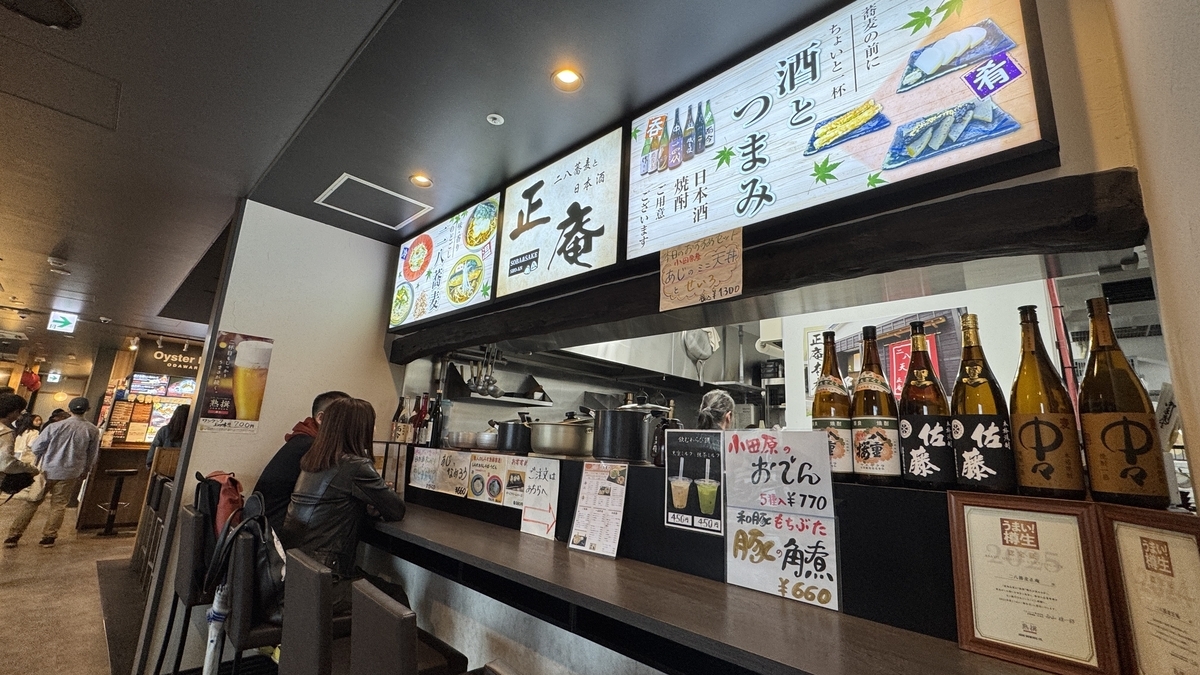 正庵のカウンター席と日本酒が並ぶ横丁の店先