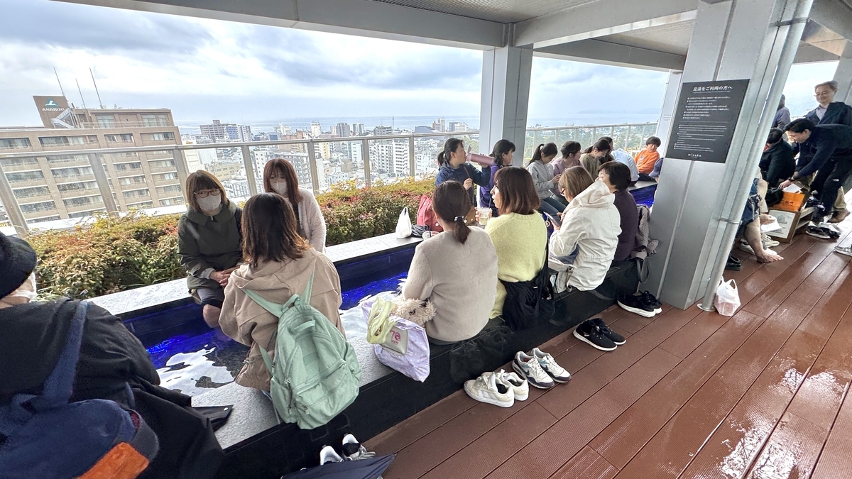 ผู้คนวางสัมภาระและรองเท้าไว้ใกล้เท้าระหว่างใช้บริการแช่เท้า