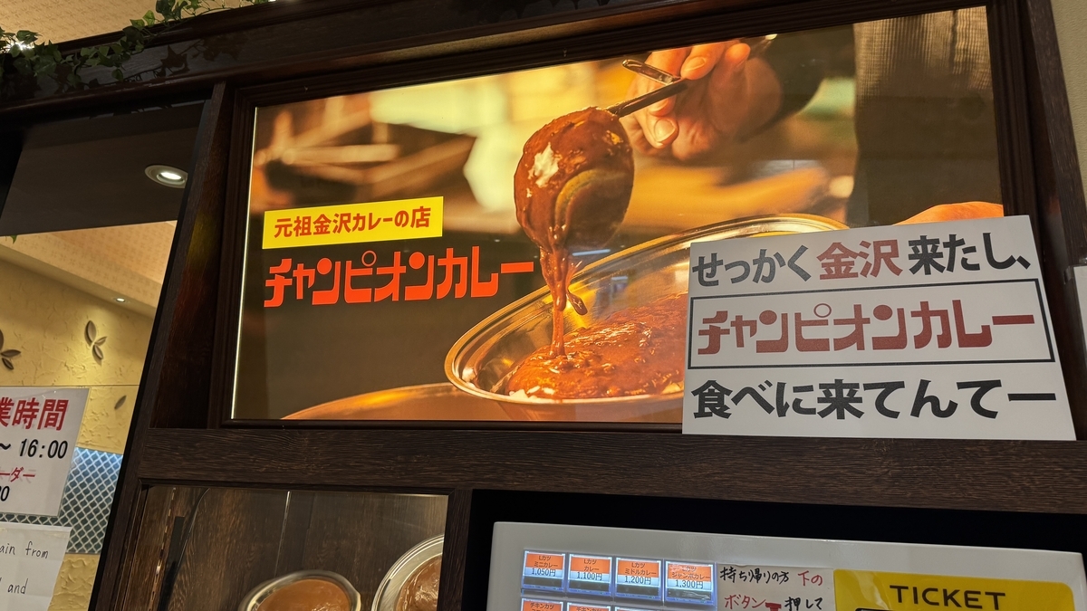 Cartel de la fachada con el logo de la tienda original del curry de Kanazawa y un mensaje en dialecto de Kanazawa