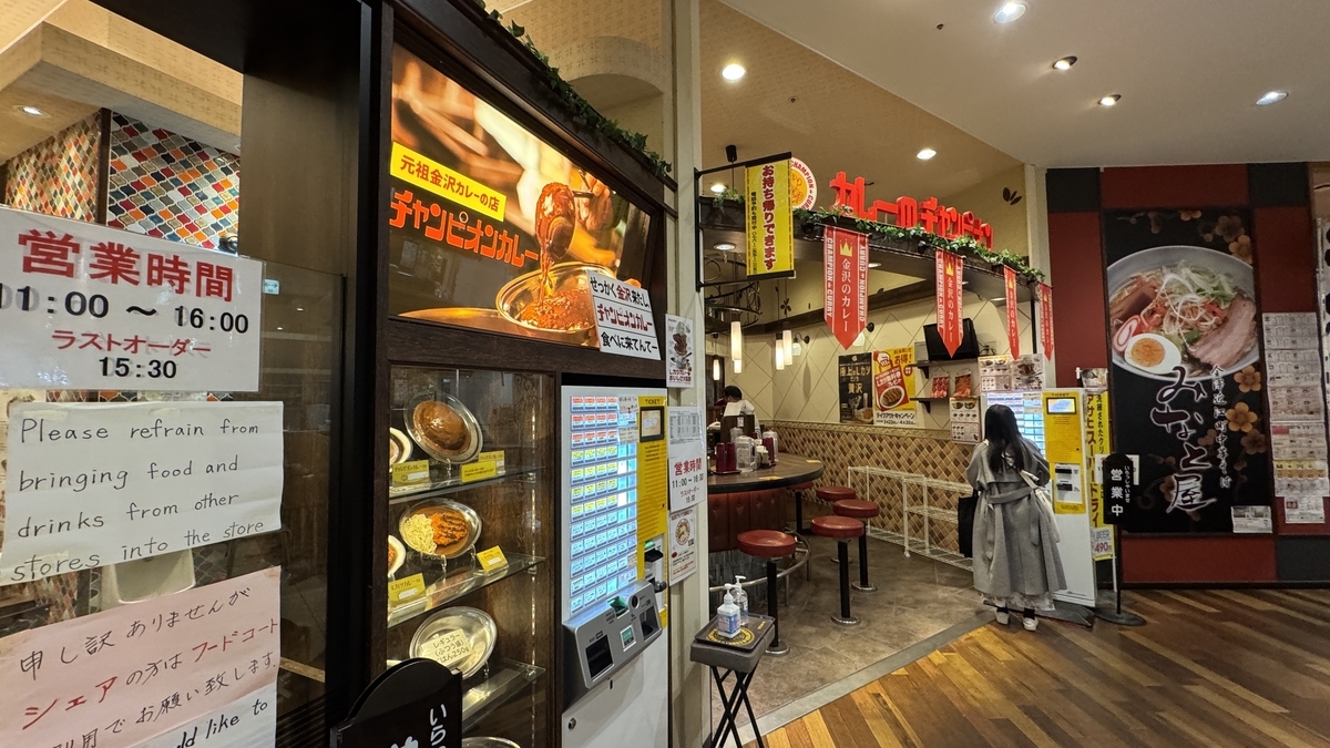 Entrada de Champion’s Curry Sucursal Omicho con la máquina expendedora y muestras de comida