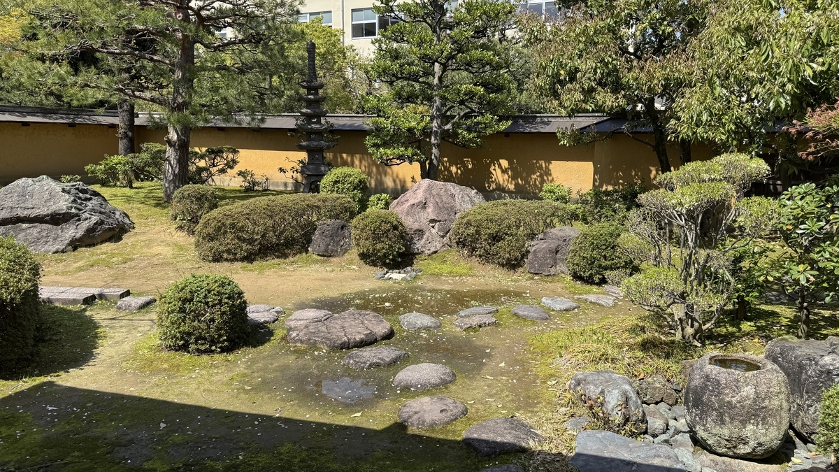 以筑地塀为背景排列着石灯笼与庭石的日本庭园