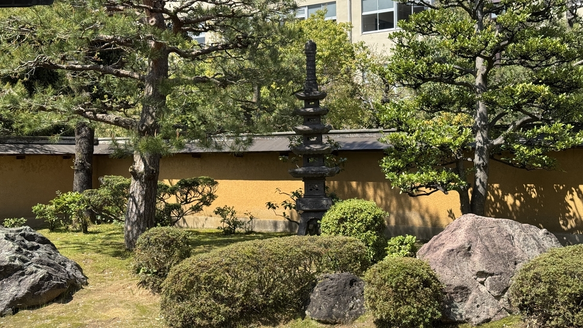 松树与修剪整齐的灌木深处屹立的日本庭园石灯笼
