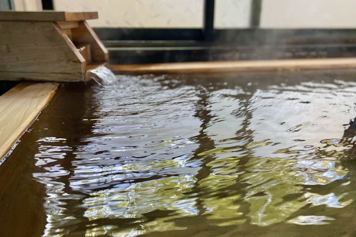 木製湯口將溫泉注入浴槽的景象
